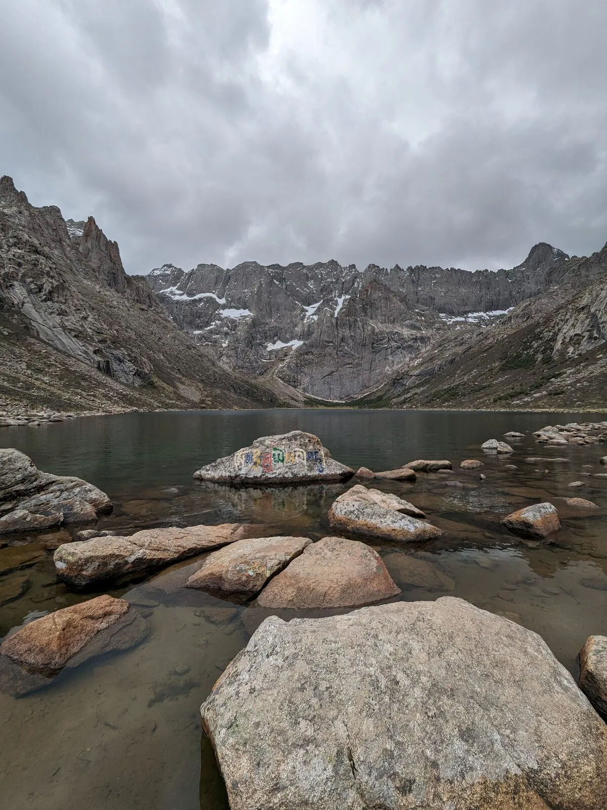 Lac d’altitude sur le plateau tibétain du Sichuan, pierre mani gravée d’un mantra sur la rive